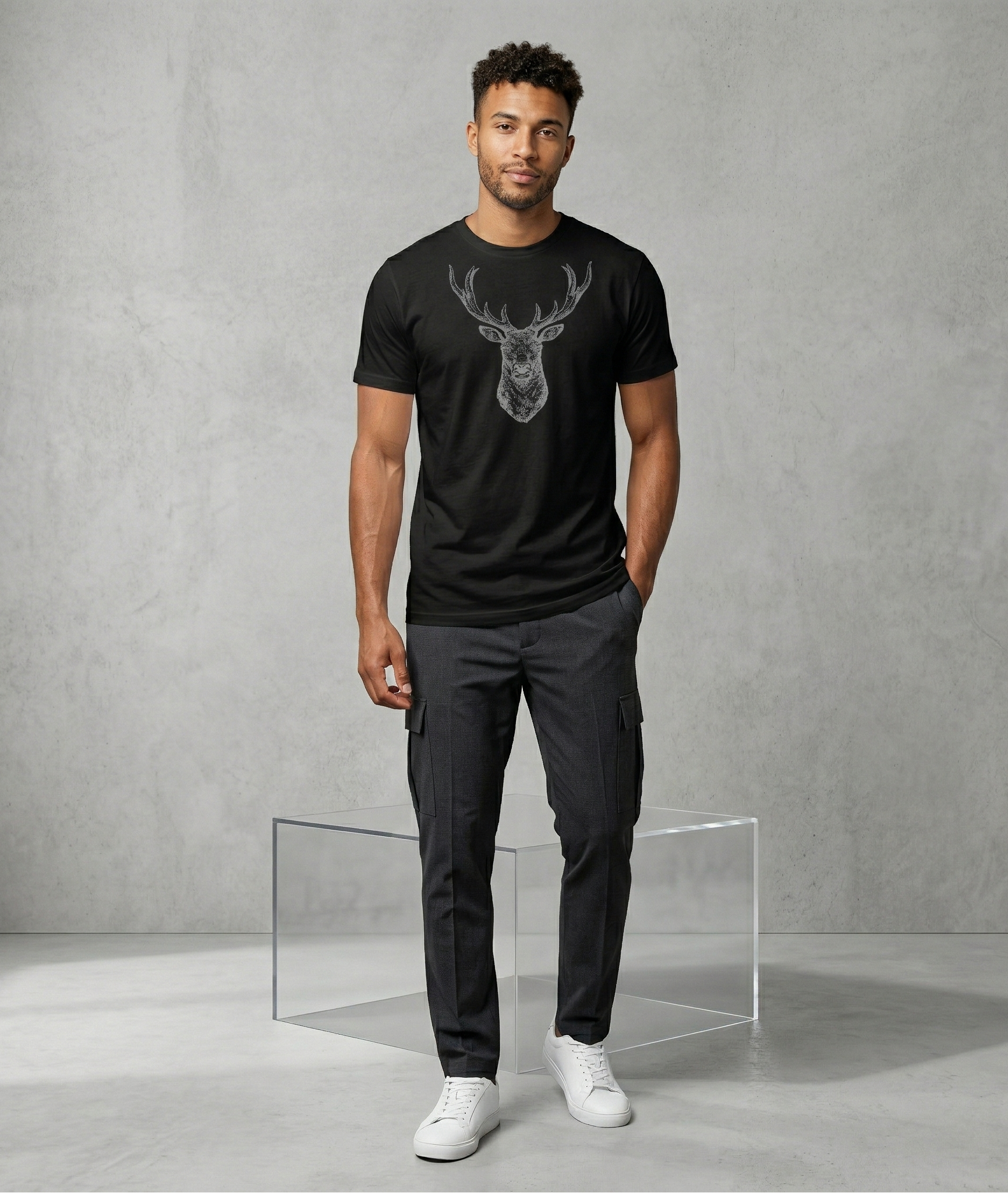 Man wearing a black t-shirt with a deer graphic and dark pants against a gray background